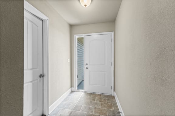 an empty hallway with a white door and a door to a closet