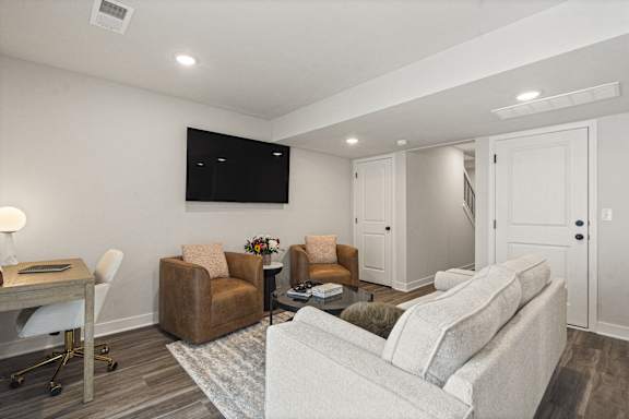 A living room with a couch, chairs, and a television.