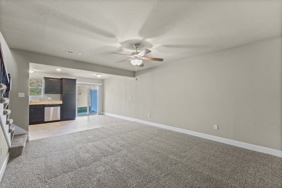 A spacious room with a ceiling fan and carpeted floor.
