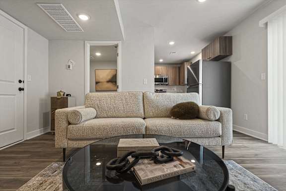 A modern living room with a beige couch and a glass coffee table.