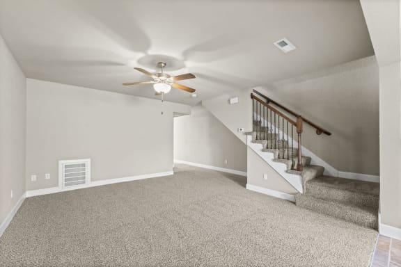 the upstairs bonus room has a ceiling fan and carpeted stairs