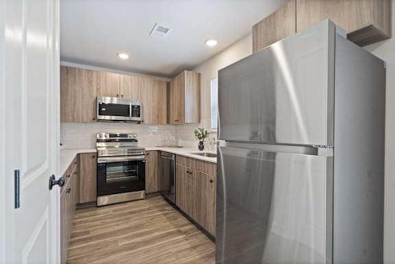 A modern kitchen with a stainless steel refrigerator and wooden cabinets.