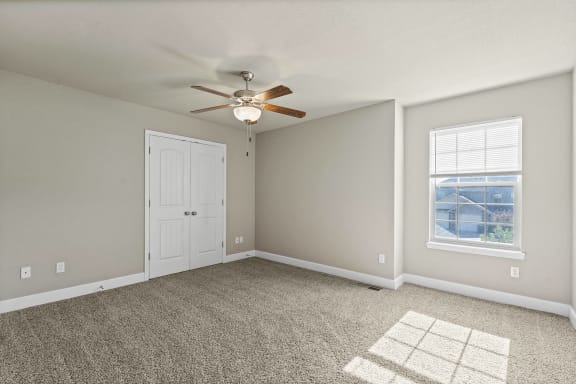 A room with a ceiling fan and a window.