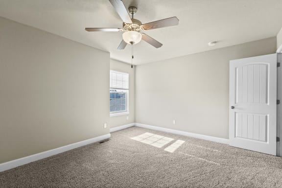 an empty living room with a ceiling fan