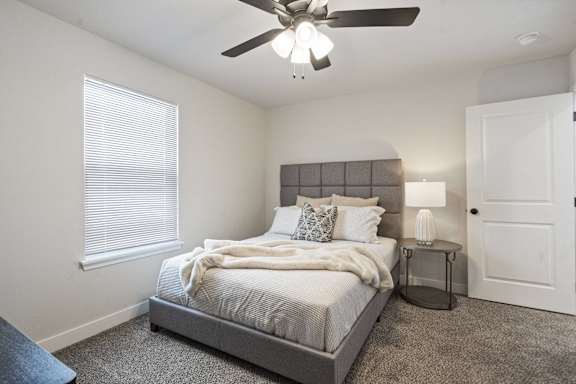 A bedroom with a bed, nightstand, and window.