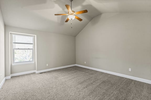 an empty room with carpet and a ceiling fan