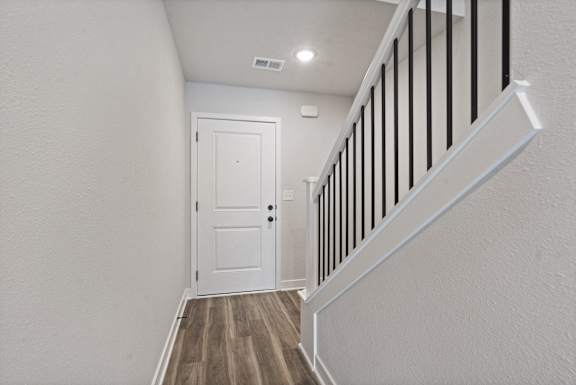 A white door is at the end of a hallway with a wooden floor.