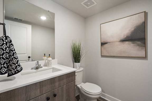 A bathroom with a toilet, sink, and a painting on the wall.