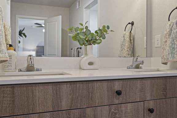 A bathroom with a white sink and a brown cabinet.