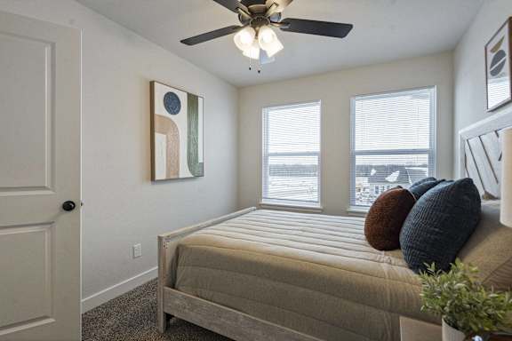 A bedroom with a bed, pillows, and a ceiling fan.