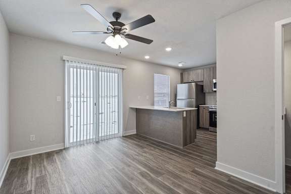 A kitchen with a refrigerator, cabinets, and a ceiling fan.