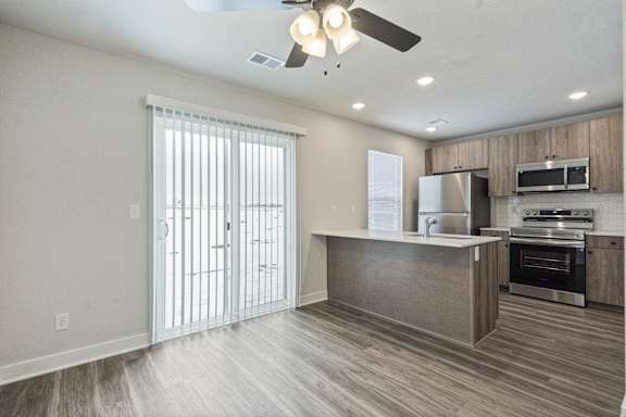 A modern kitchen with a wooden floor and stainless steel appliances.