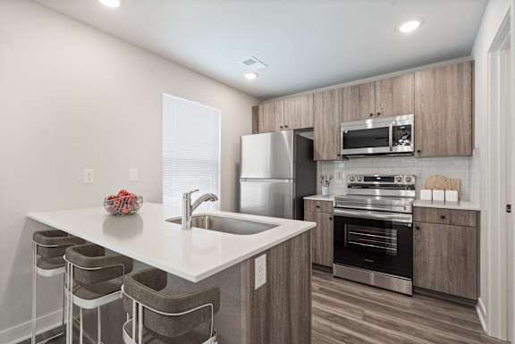 A modern kitchen with a white countertop and stainless steel appliances.