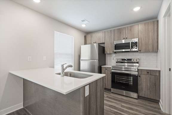 A modern kitchen with stainless steel appliances and wooden cabinets.