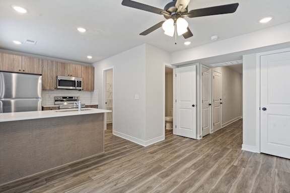 A kitchen with a refrigerator, microwave, and a ceiling fan.
