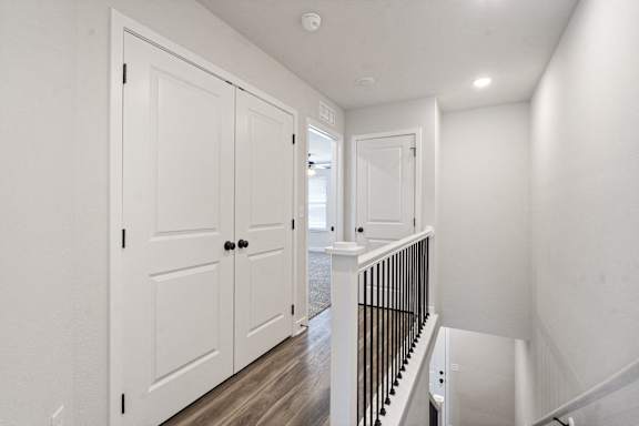 A white interior with a black railing and wooden floors.
