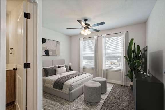 A bedroom with a bed, a ceiling fan, and a window with blinds.