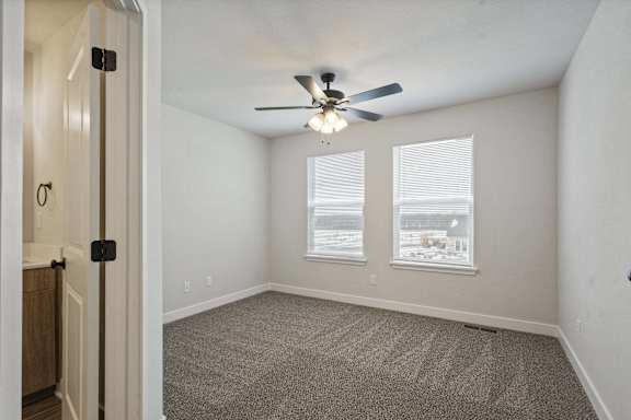 A room with a ceiling fan and carpeted floor.