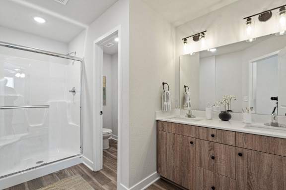 A bathroom with a walk-in shower and double sinks.
