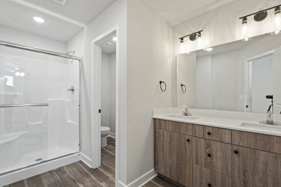 A bathroom with a walk-in shower, double sinks, and a large mirror.