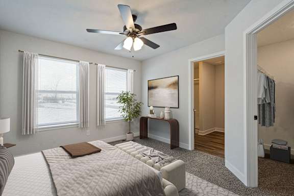 A bedroom with a large bed and a ceiling fan.