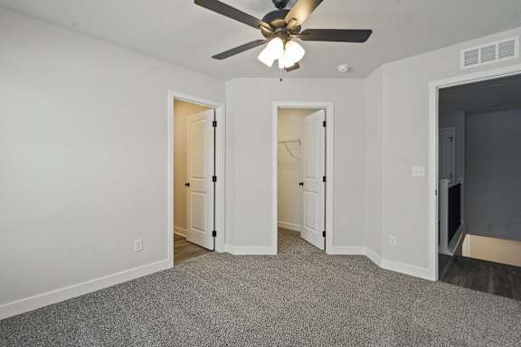 A room with a ceiling fan and carpeted floor.