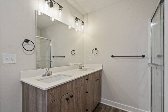 A bathroom with a sink, mirror, and lighting fixtures.