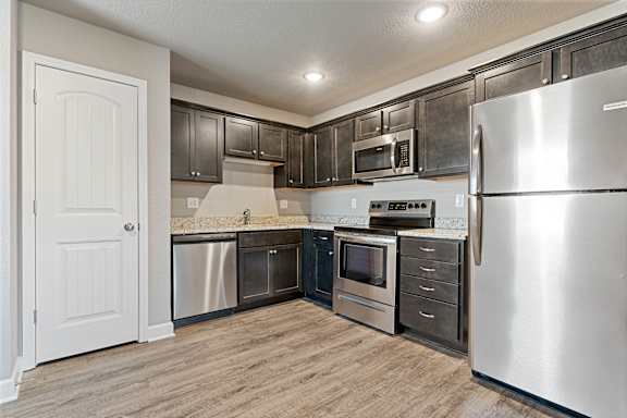 A kitchen with a refrigerator, oven, and microwave.