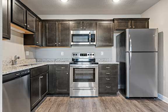 A modern kitchen with stainless steel appliances and wooden floors.