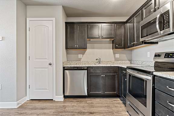 A kitchen with a white door and stainless steel appliances.