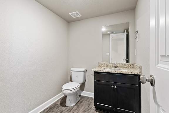 A bathroom with a toilet, sink, and vanity.