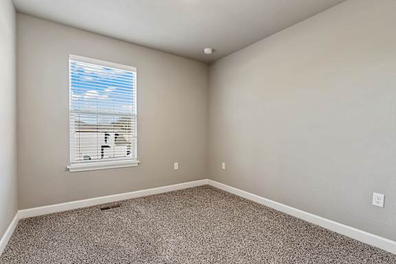 A room with a window showing a blue sky with clouds.
