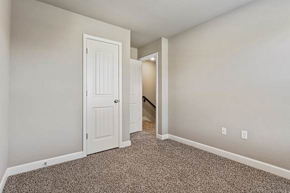 A room with a carpeted floor and a white door.
