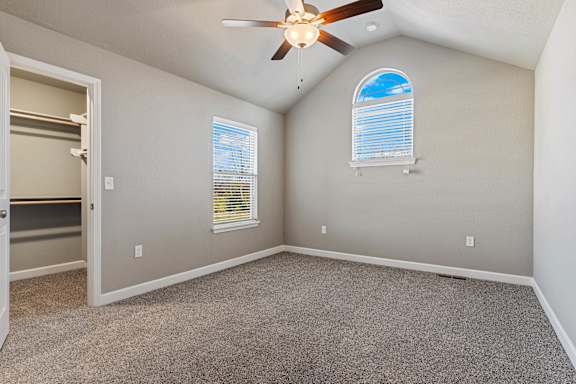 A room with a ceiling fan and two windows.