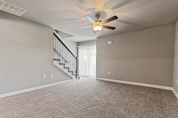 A room with a carpeted floor and a ceiling fan.