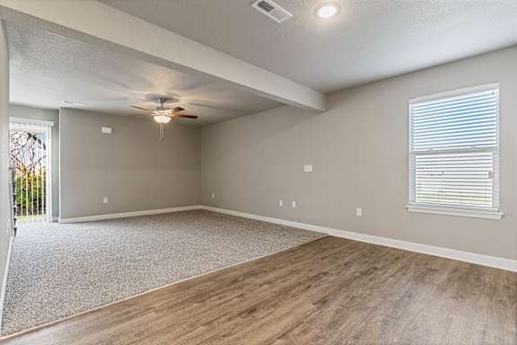 A spacious room with a ceiling fan and lighting fixture.