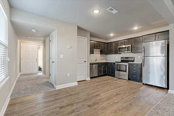 A kitchen with stainless steel appliances and wooden floors.