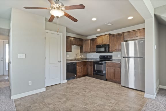 an empty kitchen with stainless steel appliances and wooden cabinets
