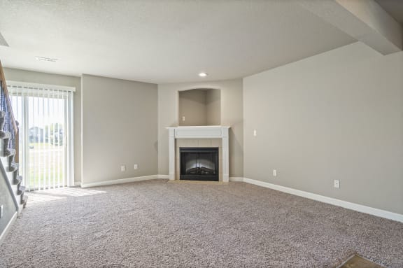 an empty living room with a fireplace and a carpeted floor