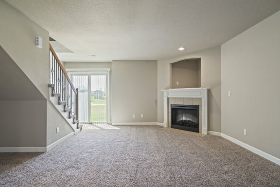 an empty living room with a fireplace and a staircase