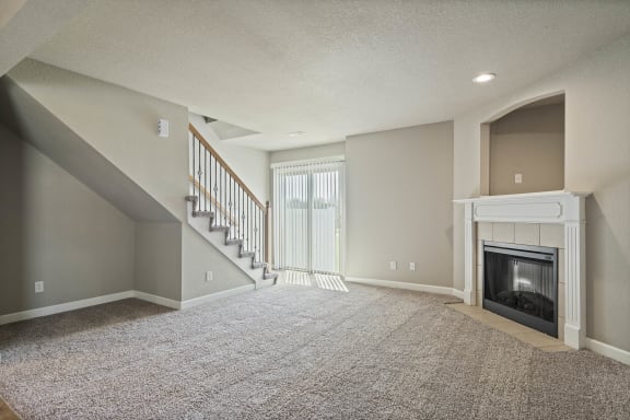 an empty living room with a fireplace and stairs