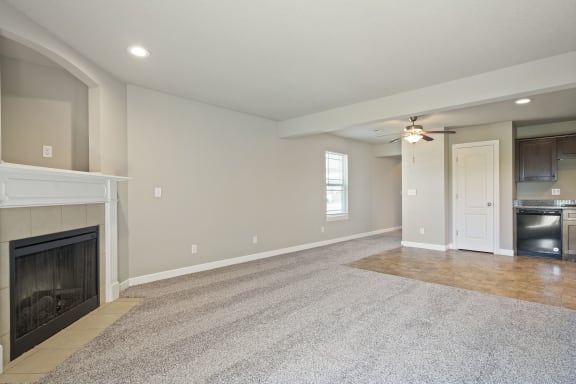 an empty living room with a fireplace and a ceiling fan