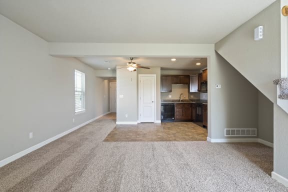 an empty living room and kitchen with a ceiling fan