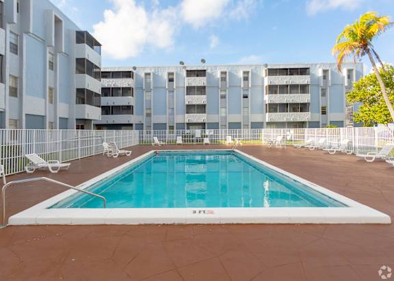 A large outdoor pool surrounded by a fence and chairs.