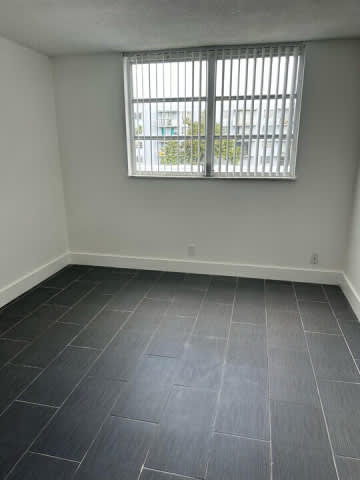 A room with a window and tiled flooring.