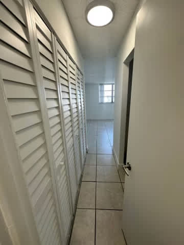 A long hallway with white walls and a light on the ceiling.