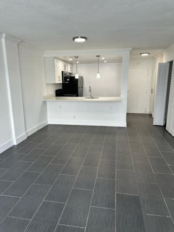 A kitchen with white cabinets and a black fridge.