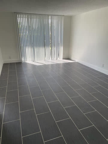A room with a black tile floor and a window with blinds.