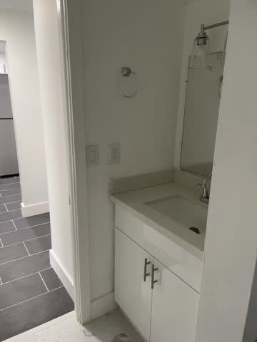 A white bathroom with a sink and mirror.