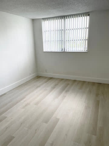 A room with a window and wooden flooring.